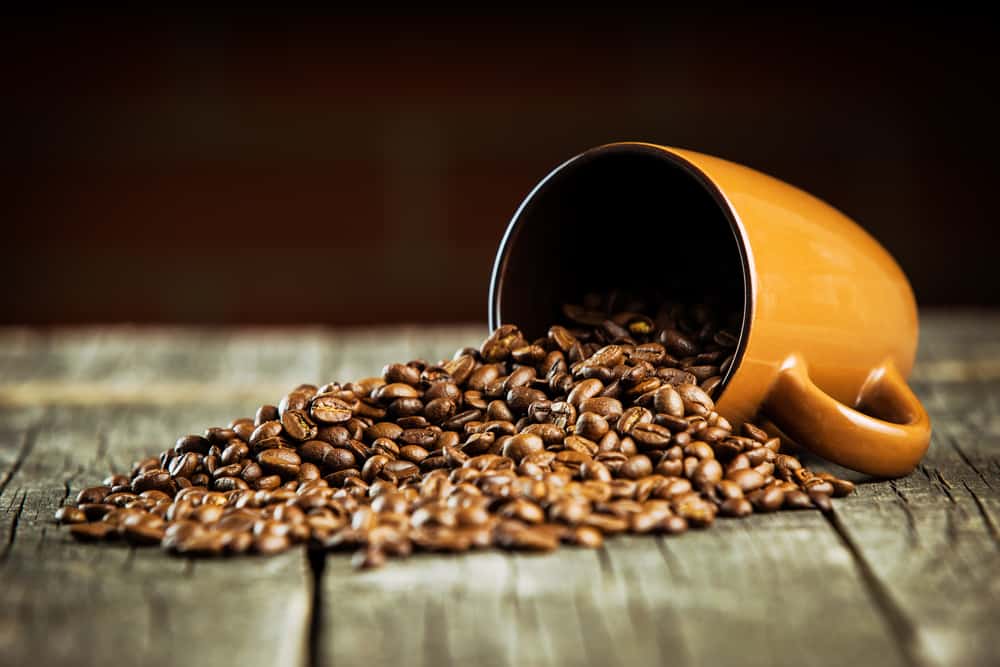 Organic coffee beans and coffee mug on wooden table.